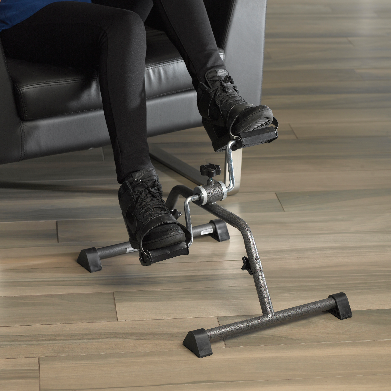 Person using a pedal exerciser on a wooden floor