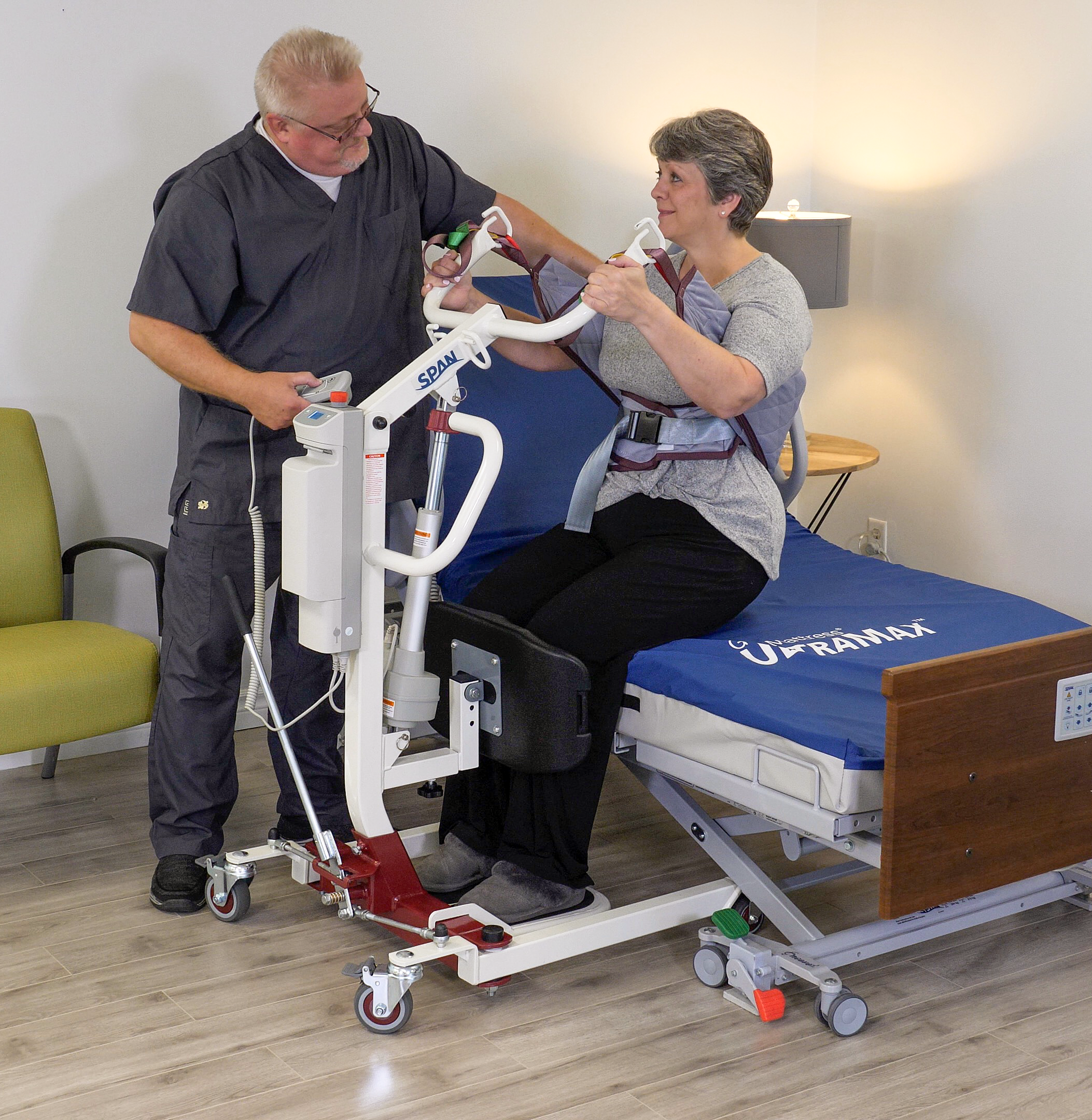 Person using a hospital bed safety rail with assistance from another person in a clinical setting.